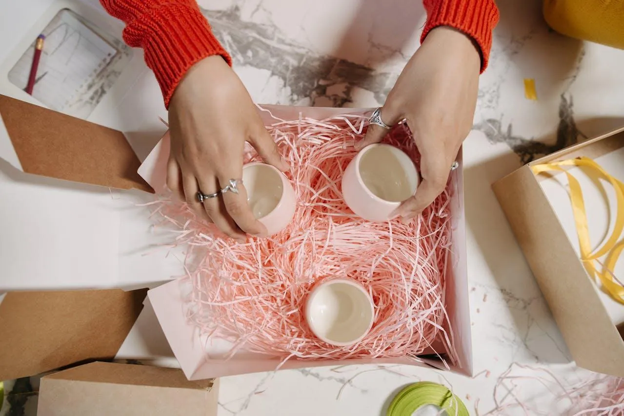 A woman packages mugs to send to a customer.